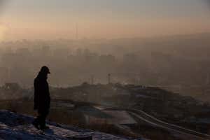 This picture taken on January 16, 2022 shows a man watching smoke hanging over houses on a polluted day in Ulaanbaatar, the capital of Mongolia. (Photo by BYAMBASUREN BYAMBA-OCHIR / AFP) (Photo by BYAMBASUREN BYAMBA-OCHIR/AFP via Getty Images)