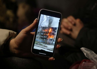 MEDYKA, POLAND - MARCH 09: Iryna Holoshchapova, a Ukrainian refugee who fled the embattled city of Mykolaiv, shows a video on her smartphone of a friend's apartment block in Mykolaiv on fire following a Russian attack as she, her son Tibor and mother Halina rest in a heated tent at the Medyka border crossing on March 09, 2022 in Medyka, Poland. Yulia said her friend was not in the building when it was struck. Over one million people have arrived in Poland from Ukraine since the Russian invasion of February 24, and while many are now living with relatives who live and work in Poland, others are journeying onward to other countries in Europe. (Photo by Sean Gallup/Getty Images)