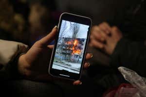 MEDYKA, POLAND - MARCH 09: Iryna Holoshchapova, a Ukrainian refugee who fled the embattled city of Mykolaiv, shows a video on her smartphone of a friend&#039;s apartment block in Mykolaiv on fire following a Russian attack as she, her son Tibor and mother Halina rest in a heated tent at the Medyka border crossing on March 09, 2022 in Medyka, Poland. Yulia said her friend was not in the building when it was struck. Over one million people have arrived in Poland from Ukraine since the Russian invasion of February 24, and while many are now living with relatives who live and work in Poland, others are journeying onward to other countries in Europe. (Photo by Sean Gallup/Getty Images)