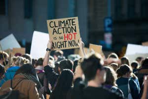 &quot;Climate Action is so hot right now&quot; text written on a sign at student climate change protest in Melbourne Australia. Group of protesters marching down street against global warming. Focus on sign.; Shutterstock ID 1992990047; purchase_order: -; job: -; client: -; other: -