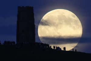 GLASTONBURY, ENGLAND - JUNE 20: A full moon rises behind Glastonbury Tor as people gather to celebrate the summer solstice on June 20, 2016 in Somerset, England. Tonight&#039;s strawberry moon, a name given to the full moon in June by Native Americans because it marks the beginning of strawberry picking season, last occurred on the solstice on June 22, 1967 and it will not happen again on the summer solstice for another 46 years until June 21, 2062. (Photo by Matt Cardy/Getty Images)