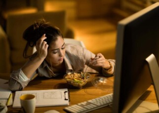 Distraught woman having salad for dinner while working on computer in the evening at home. ; Shutterstock ID 1581071689; purchase_order: -; job: -; client: -; other: -