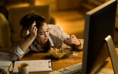 Distraught woman having salad for dinner while working on computer in the evening at home. ; Shutterstock ID 1581071689; purchase_order: -; job: -; client: -; other: -