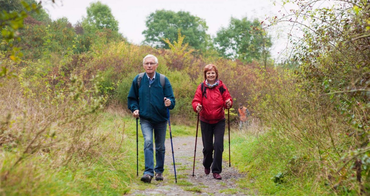 EJMAXP Senior couple Nordic walking on rocky trail in the nature.