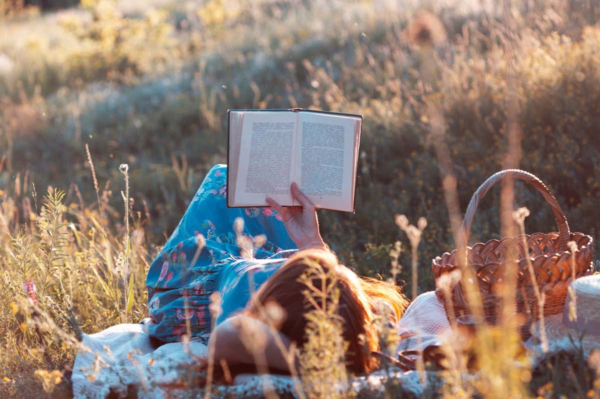 Summer - girl reads a book on a picnic in a meadow in the forest. ; Shutterstock ID 1774750949; purchase_order: -; job: -; client: -; other: -