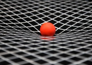 A simulation of gravity showing curved space-time. The ball represents the sun and is resting on a sheet of plastic that stretches under its weight. The curved sheet of plastic demonstrates the way a gravity curves space.
