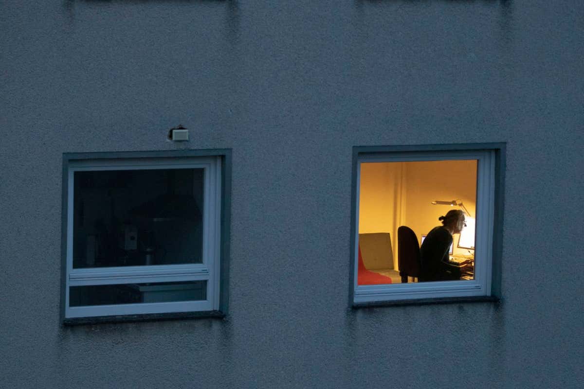 BONN, GERMANY - DECEMBER 23: A woman is seen illuminated in the window of a residential building on December 23, 2021 in Bonn, Germany. (Photo by Ulrich Baumgarten via Getty Images)