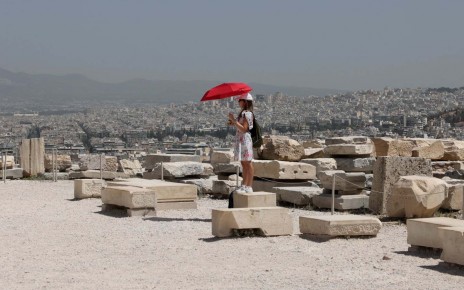 ATHENS, GREECE - JULY 23: A woman use umbrella to protect themselves from the sun as they visit the Parthenon temple atop the Acropolis hill, during a hot weather in Athens, Greece on July 23, 2023. Visits to certain tourist sites, including the Acropolis, home to the Parthenon temple, in Athens, temporarily closed due to a fierce heatwave. (Photo by Costas Baltas/Anadolu Agency via Getty Images)