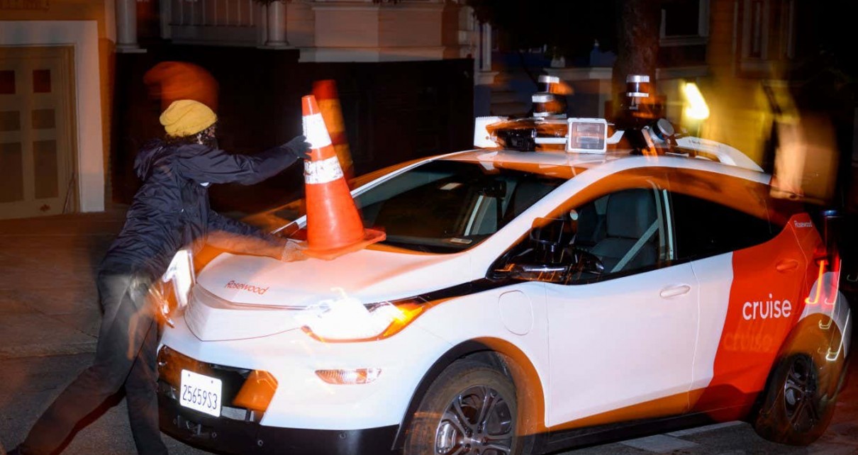 Members of SafeStreetRebel, a group of anonymous anti-car activists, place a cone on a self-driving robotaxi to disable it in San Francisco, California on July 11, 2023. Members of SafeStreetRebel, a group of anonymous anti-car activists, have been actively calling for participants to help protest the spread of robotaxis for malfunctioning and blocking traffic. (Photo by Josh Edelson / AFP) (Photo by JOSH EDELSON/AFP via Getty Images)