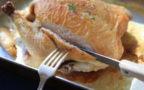 F3875E Slicing into the breast of a freshly roasted chicken in pan with juices