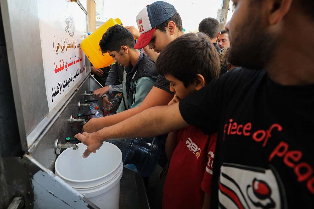 Palestinians line up to fill water cannisters in Gaza