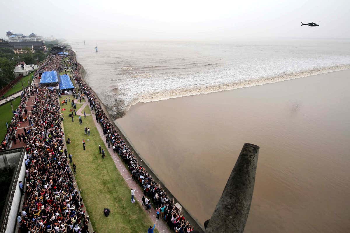 Mandatory Credit: Photo by Shutterstock (9120931j) Visitors and local residents throng to watch the tidal bore of the Qiantang River in Haining city, east China's Zhejiang province Qiantang River tidal bore, Haining city, Zhejiang province, China - 06 Oct 2017 The Qiantang River tidal bore is as famous as the ones on the Ganges in India and the Amazon in Brazil. The river, originating in the border region of Anhui and Jiangxi provinces, runs for 459 kilometers through the coastal Zhejiang province, passing through the provincial capital Hangzhou before flowing into the East China Sea via the Hangzhou Bay. The river is the southern terminus of the ancient Grand Canal that links five major rivers in China from north to south, and enables water-borne traffic to travel inland from Hangzhou as far north as Beijing.While the Hangzhou Bay at the mouth of the Qiantang is about 100 km wide, the river narrows to a mere 2-3 km at one point??its Yanguan section. And as the tidal waters are blocked by the narrow river passage, pressure builds up from behind until a tidal bore is formed, creating a high water wall.