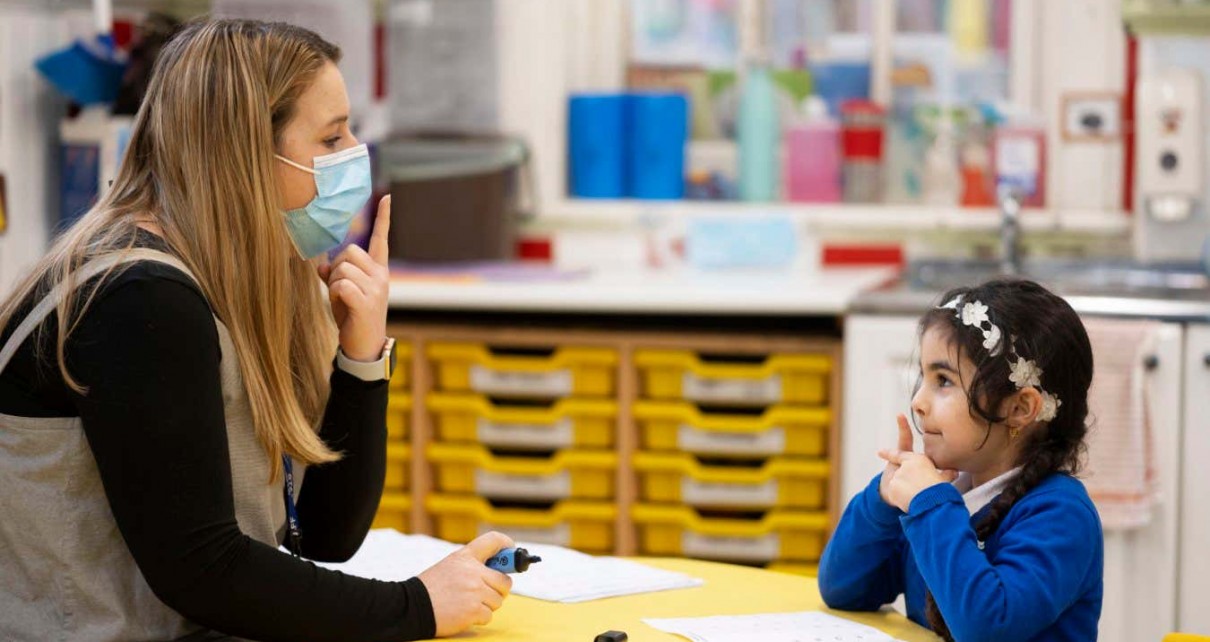 CARDIFF, WALES - FEBRUARY 23: A teacher wearing a face mask teaches a child at Roath Park Primary School on February 23, 2021 in Cardiff, Wales. Children aged three to seven began a phased return to school on Monday. Wales' education minister Kirsty Williams has said more primary school children will be able to return to face-to-face learning from March 15 if coronavirus cases continue to fall. (Photo by Matthew Horwood/Getty Images)
