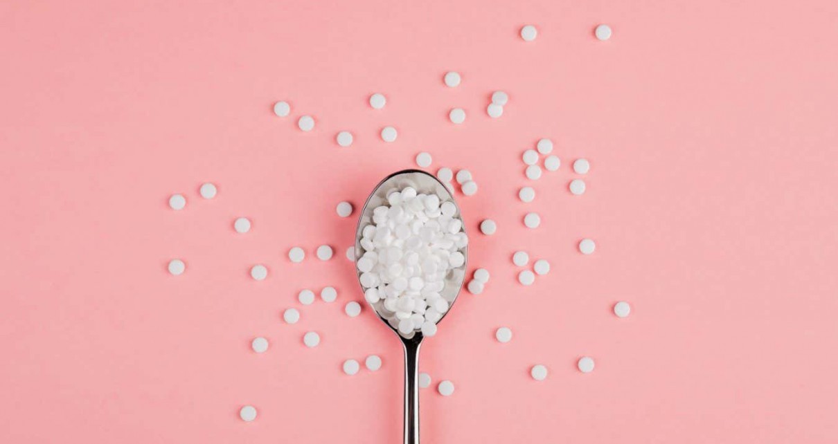 Sugar-replacing tablets with a spoon on a pink background.; Shutterstock ID 1326637646; purchase_order: -; job: -; client: -; other: -