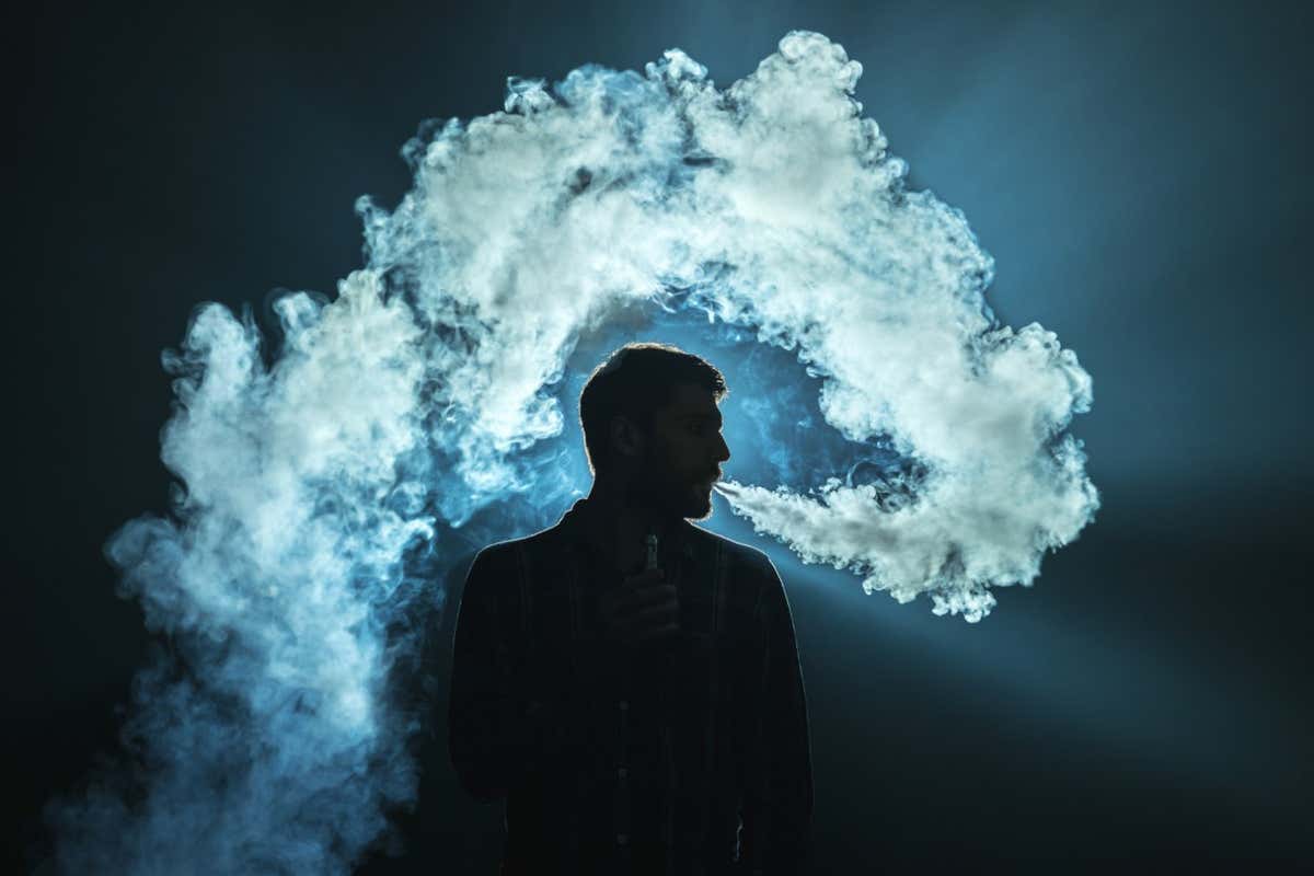 The man smoke an electronic cigarette on the dark background; Shutterstock ID 519015292; purchase_order: -; job: -; client: -; other: -