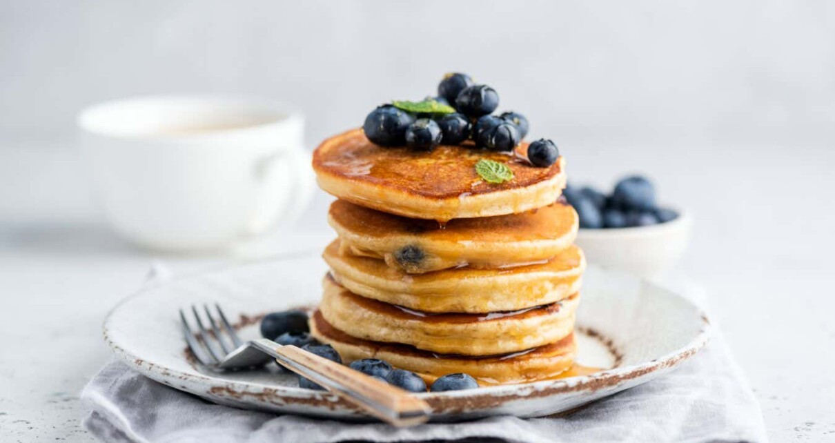 Tasty pancakes with blueberries and honey on a plate. Grey background; Shutterstock ID 1784577482; purchase_order: -; job: -; client: -; other: -