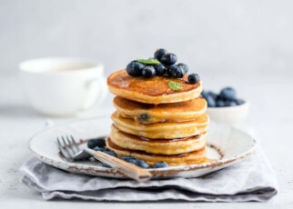 Tasty pancakes with blueberries and honey on a plate. Grey background; Shutterstock ID 1784577482; purchase_order: -; job: -; client: -; other: -