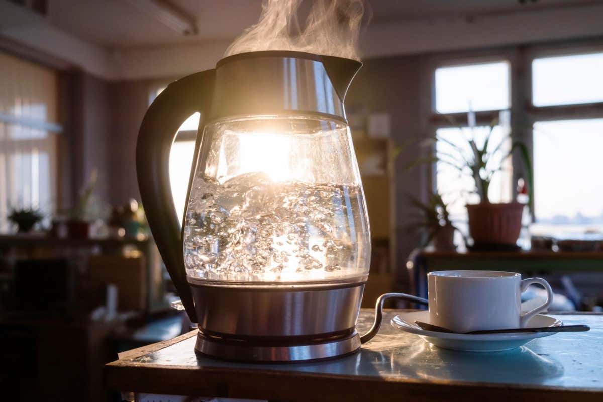 A transparent kettle of water boils as the sun shines through the window