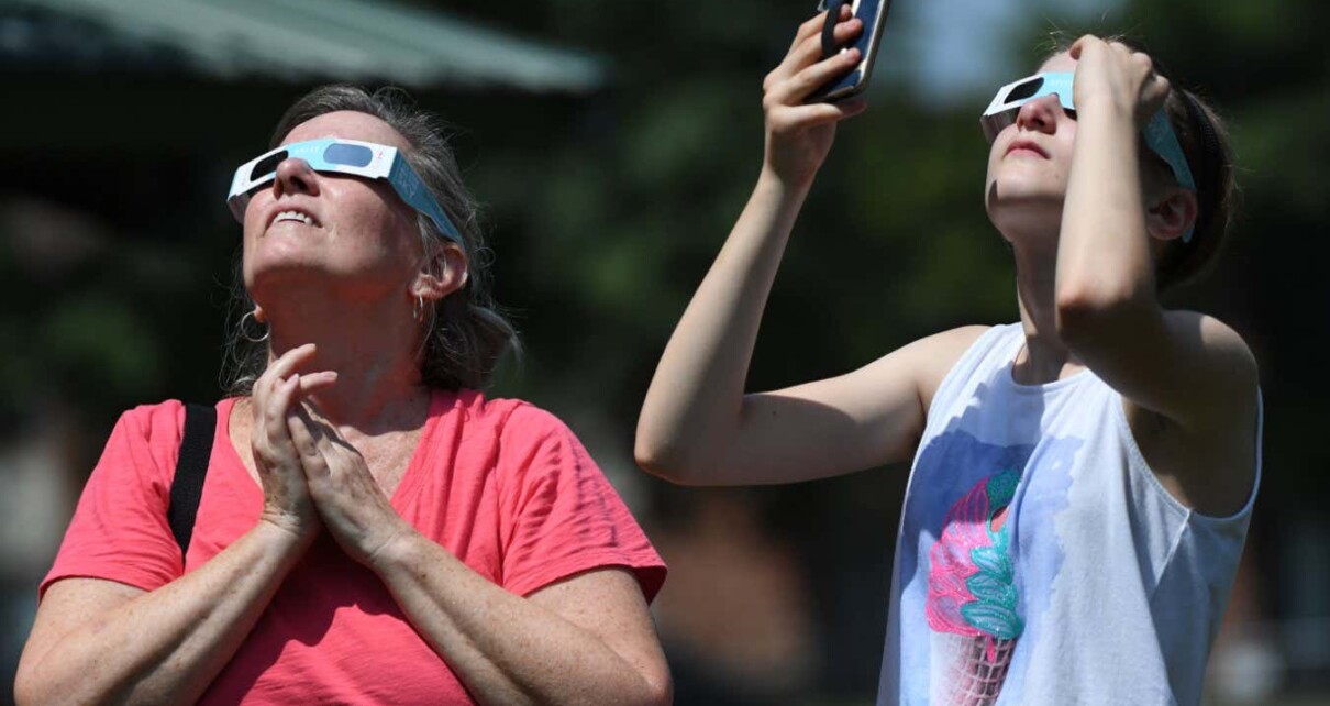 Two people viewing an eclipse wearing eclipse glasses