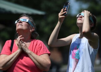 Two people viewing an eclipse wearing eclipse glasses